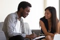 Asian ethnicity woman instructing african colleague explain project details