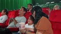 An Asian family audience enjoys watching cinema together at movie theaters.