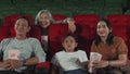 An Asian family audience enjoys watching cinema together at movie theaters.