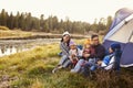 Asian family on a camping trip relax outside their tent Royalty Free Stock Photo