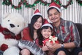 Asian family in Christmas interior.Happy mother father and  daughter holding a gift box with smile Royalty Free Stock Photo