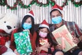 Asian family in Christmas interior.Happy mother father and  daughter wearing face mask and holding a gift box with smile Royalty Free Stock Photo