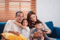 Asian family consisting of parents, happy son and daughter watching TV or movie together on sofa in living room at home. enjoy Royalty Free Stock Photo