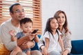 Asian family consisting of parents, happy son and daughter watching TV or movie together on sofa in living room at home. enjoy Royalty Free Stock Photo