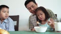 Asian family eating breakfast together, daughter eating a large scoop