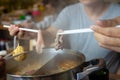 Asian family eating food in hot pot. People enjoy shabu sukiyaki barbecue. Hand hold meat with chopsticks over boiling water. Royalty Free Stock Photo