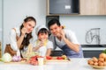 Asian family with father, mother and cute little girl daughter  in chef`s hats are having fun while cooking in kitchen at home Royalty Free Stock Photo