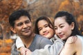 Asian family, father, mother and daugther having goodtime together in park in autumn season