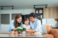 Asian family with father, mother and her daughter reading fairy tail story book on sofa at home together and pointing on the book Royalty Free Stock Photo