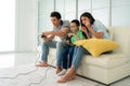 Asian family father and son having fun playing computer console games together in living room at home with handset controllers and Royalty Free Stock Photo