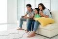 Asian family father and son having fun playing computer console games together in living room at home with handset controllers and Royalty Free Stock Photo