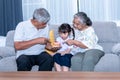 Asian family, Grandpa and elderly grandmother, persuading granddaughter to eat a snack, is sweet donut