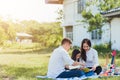 Asian family having fun and enjoying outdoor on picnic blanket reading book in park Royalty Free Stock Photo