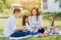 Asian family having fun and enjoying outdoor on picnic blanket reading book in park Royalty Free Stock Photo