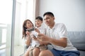 Asian family having fun playing computer console games together, Father and son have the handset controllers and the mother is ch Royalty Free Stock Photo