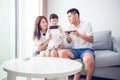 Asian family having fun playing computer console games together, Father and son have the handset controllers and the mother is Royalty Free Stock Photo