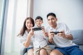 Asian family having fun playing computer console games together, Father and son have the handset controllers and the mother is Royalty Free Stock Photo