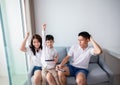 Asian family having fun playing computer console games together, Father and son have the handset controllers and the mother is Royalty Free Stock Photo