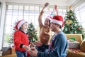 Asian family having fun Santa hats in front couch at home celebrating at Christmas the paper and gift box with Christmas tree in Royalty Free Stock Photo