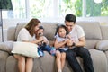 Asian family having fun in singing karaoke on sofa in living room together. Mother teaching son child and looking he singing song Royalty Free Stock Photo