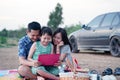 Asian family having a picnic and looking laptop in the park with smile and happy Royalty Free Stock Photo