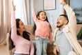 Asian Family With Little Daughter Raising Hands Playing At Home