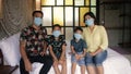 Asian family in medical masks during home quarantine. Indonesian or malasian parents and kids wearing protective mask at