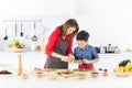 Asian family mom in red shirt and black apron is teaching her s