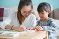 Asian family with mother and daughter doing together activities at home. happy mom and child doing learning and drawing on table Royalty Free Stock Photo