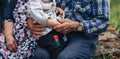 Asian family in the open air. The grandson is sitting on the lap of his grandfather. The child spends time with his