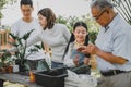 Asian family planting tree in garden at home. Parent with kid and grandfather