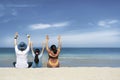 Asian family sitting relaxing on white sand beach with turqouise blue sea in sunny day Royalty Free Stock Photo