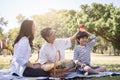 Asian family with son sitting hold apple above his head in the public park. Concept of lifestyle at happy in family holiday Royalty Free Stock Photo