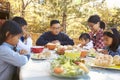 Asian family at a table on a deck say a prayer before eating Royalty Free Stock Photo