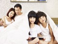 Asian family with two children having fun in bedroom Royalty Free Stock Photo