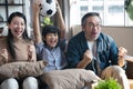 Asian family watching football sports games on TV and reacting happy exiting when team Shoot the ball into the goal.