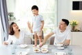 Asian family watching their kid as he is determined and proud to finally stand on the dining table.