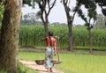 Asian farmer carrying agricultural tools spade, bowls on his neck aiming to work in the nearest farmland