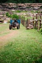 Asian farmer driving agriculture tractor or wheel plough on dirt road