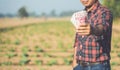 Asian farmer holding Chinese banknote RMB in the field of tobacco tree