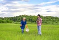 asian farmer is sowing fertilizer on rice field with young asian smart farmer holding digital tablet observing in paddy field