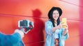 Asian fashion woman vlogging and using mobile smart phone outdoor - Happy Chinese trendy girl having fun making video Royalty Free Stock Photo