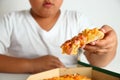 Asian fat boy eating pizza that has too much flour and fat. Royalty Free Stock Photo