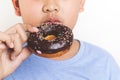 Asian fat boy holds a chocolate-coated donut He enjoys eating. Royalty Free Stock Photo