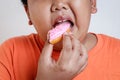 Asian fat boy holds a strawberry-coated donut He enjoys eating. Royalty Free Stock Photo