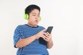 Asian fat boy standing playing smartphone Wearing headphones to music Royalty Free Stock Photo