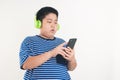 Asian fat boy standing playing smartphone Wearing headphones to music watching him happy. Royalty Free Stock Photo