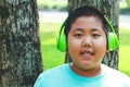 Asian Fat Boy Wearing green music headphones, standing against a happy tree. Royalty Free Stock Photo