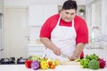 Asian fat man cutting a cucumber in the kitchen Royalty Free Stock Photo