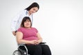 Asian fat woman sitting on a wheelchair Have a female doctor to help take care of inquiring about the illness.